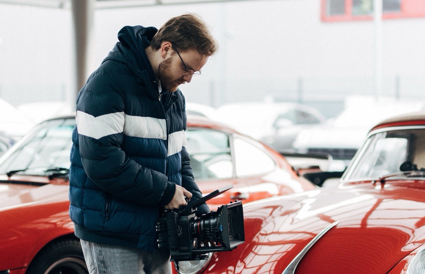 Daniel prüft die Kamera zwischen roten Oldtimern
