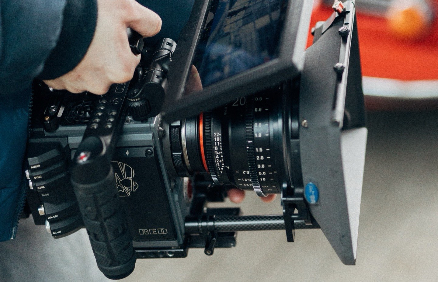 Cinema-Kamera mit Objektiv und Matte-Box in der Hand